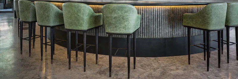 Bar counter with green upholstered stools at Sean Connolly Restaurant
