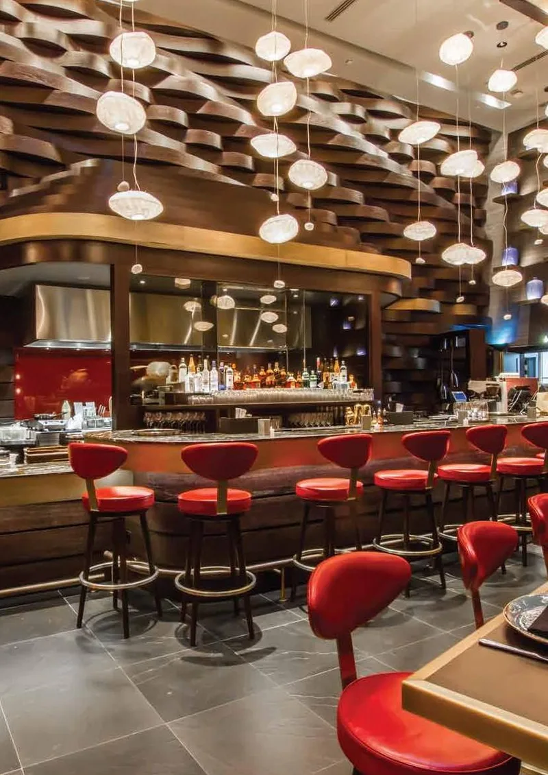 Bar with red stools and pendant lights at China Grill, Four Seasons Dubai