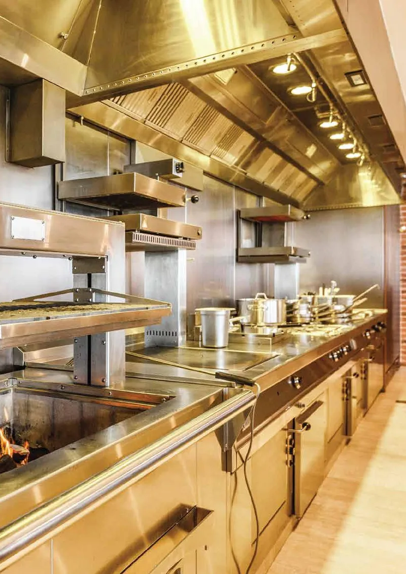 Brass-finished cooking line under a stainless extraction canopy at The St. Regis Downtown Dubai