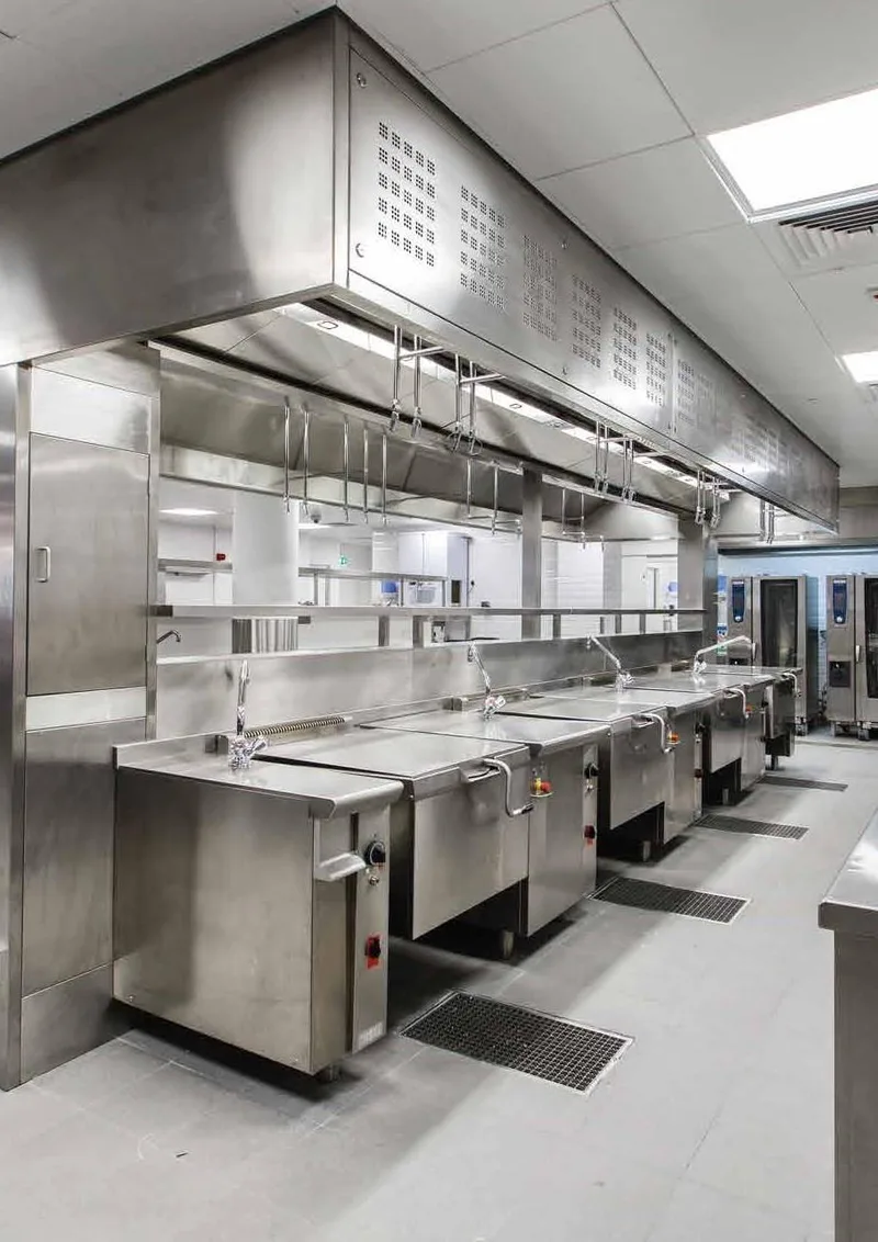 Large school kitchen with tilting kettles under extraction canopies